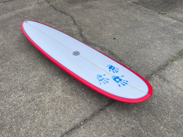 Red and white mid length surfboard with hand prints