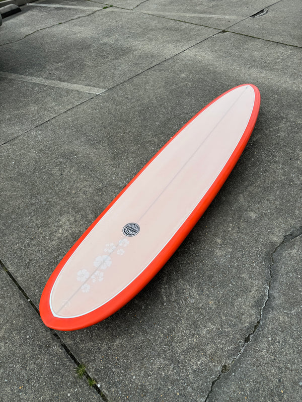 orange and white mid length surfboard with floral print