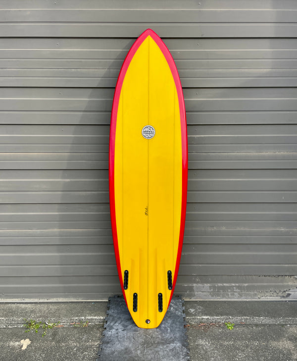 red and yellow mid length quad fin surfboard