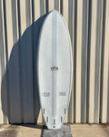The image shows a white surfboard with the brand name "Runyon" printed on it. The board has a distinct single fin design and appears to be a high-quality, professionally shaped surf craft. The background shows a corrugated metal or wood siding, suggesting the surfboard is resting against a wall or structure.