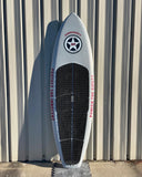 A white surfboard with a black traction pad, red "GUNRUNNER 6" logo, and "269" printed on the deck, leaning against a wall.