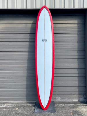 A red framed, white center, glider surfboard leaning against a metal garage door. Runyo logo in the center. 