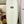 A classic-white Mini Hammer Runyon Surfboard, standing vertically in a workshop with surfboard blanks in the background. 