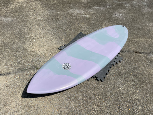 Pink and Teal Pastel Colored Fully Auto Surfboard laying on cement 