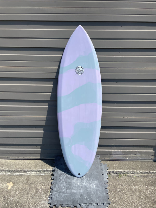 Pastel Pink and Teal Fully Auto Surfboard, blob design. Standing against a metal wall