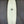 An eggshell white Mini hammer surboard laying on a workshop floor. The Design is Asymmetrical, and has a fish tail. 